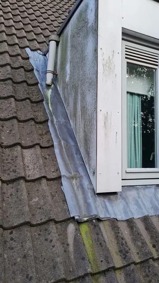 Zijwang van een dakkapel met groene aanslag op het kunststof voor de reiniging
