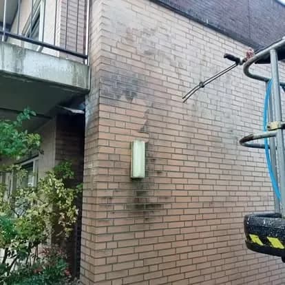 Bakstenen gevel van een bedrijfspand met donkere roetstrepen voor de reiniging