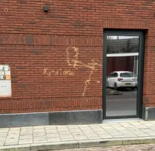 Bakstenen gevel naast een entree met verse graffiti erop